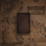 A leather notebook placed on a stylized map of Westeros from a fictional fantasy world.